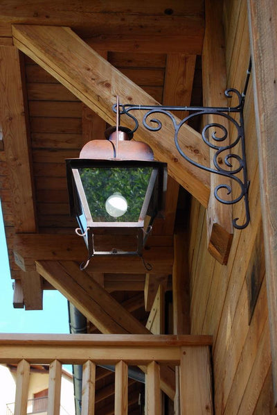 Lanterne à suspendre Uzes patine naturelle mise en situation accrochée sur le mur d'une maison